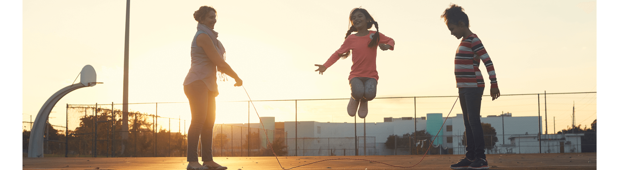 A family jumping rope at sunset.