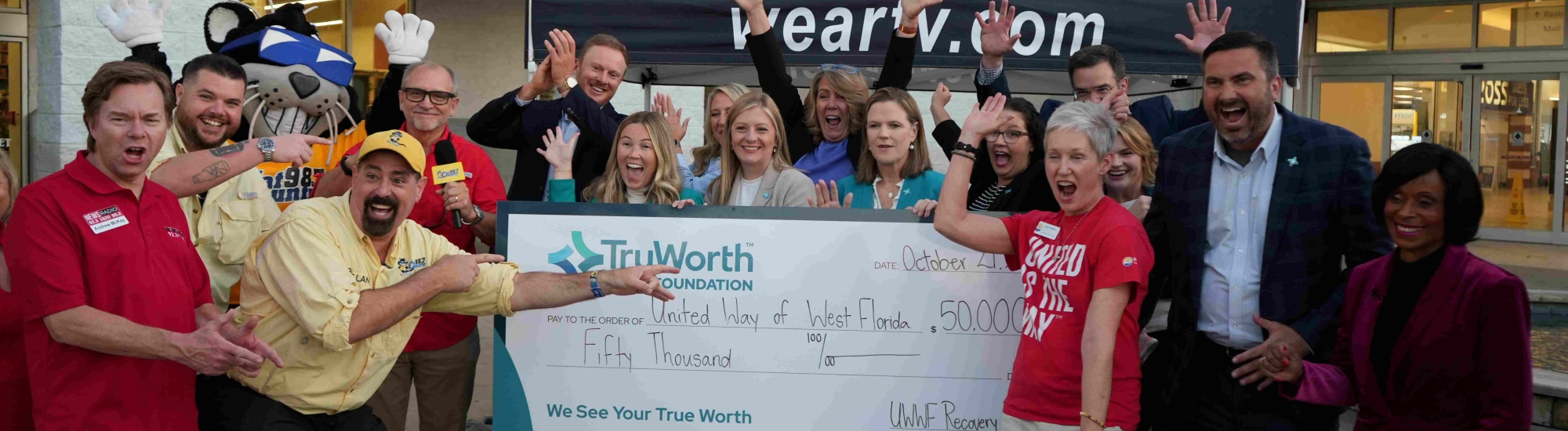 A group of people holding a check from TruWorth bank.