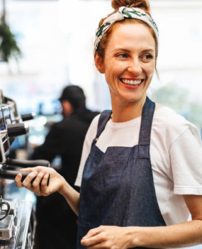 A barista making coffee and smiling.