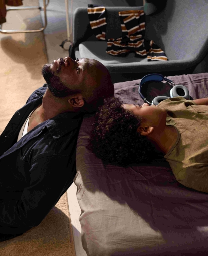 Father and son leaning on a bed.