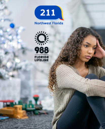 A girl sitting by a Christmas tree, looking sad.