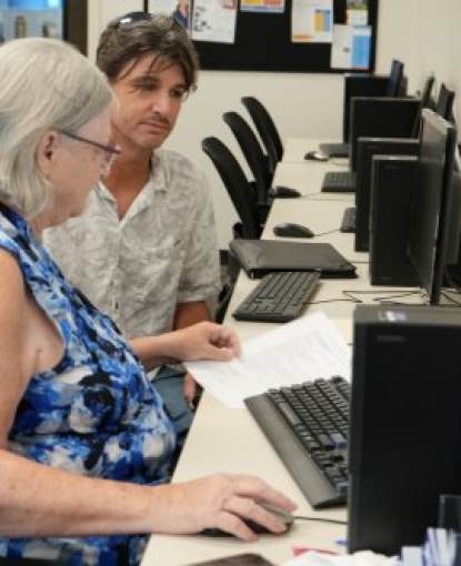 A photo of a woman and a man sitting at a computer. The woman is typing while the man looks at the screen.